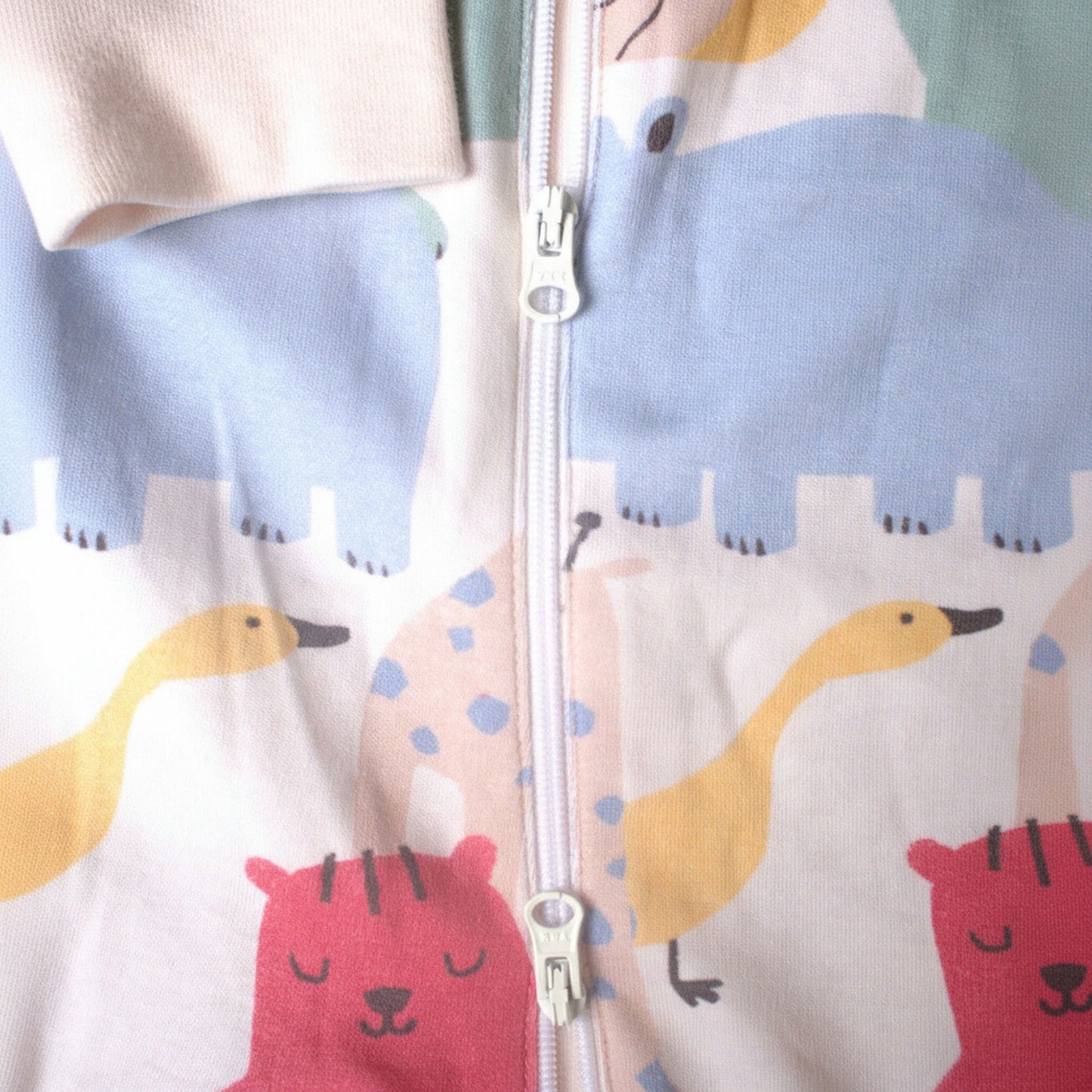 Detaljbild av ekologisk babypyjamas från kollektionen Safari Vänner med dragkedja vid nederkanten och färgglatt safarimönster