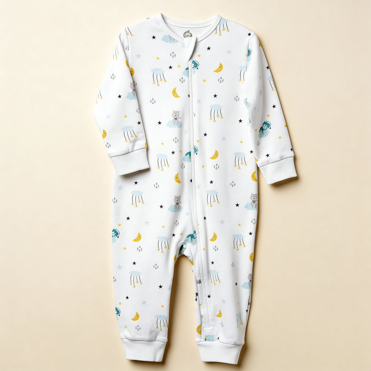 Ekologisk babypyjamas från kollektionen Himlens Vänner, vit med himmelskt mönster, flatlay på beige bakgrund