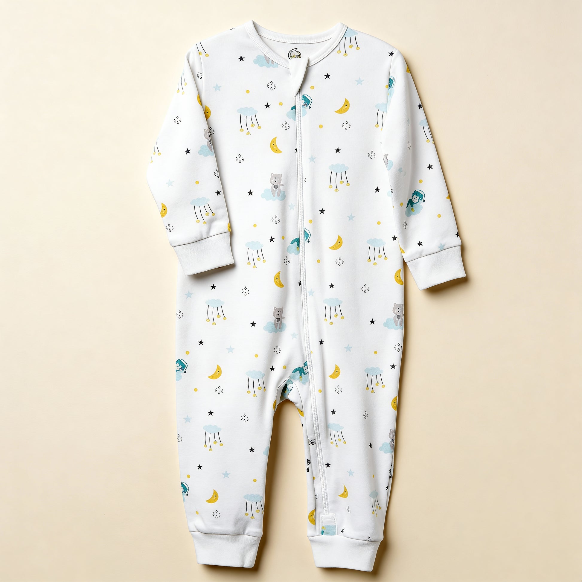 Ekologisk babypyjamas från kollektionen Himlens Vänner, vit med himmelskt mönster, flatlay på beige bakgrund