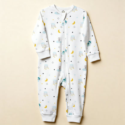 Ekologisk babypyjamas från kollektionen Himlens Vänner, vit med himmelskt mönster, flatlay på beige bakgrund