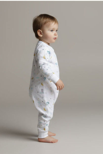 Barn i ekologisk babypyjamas från kollektionen Himlens Vänner, vit med himmelskt mönster, sedd från sidan