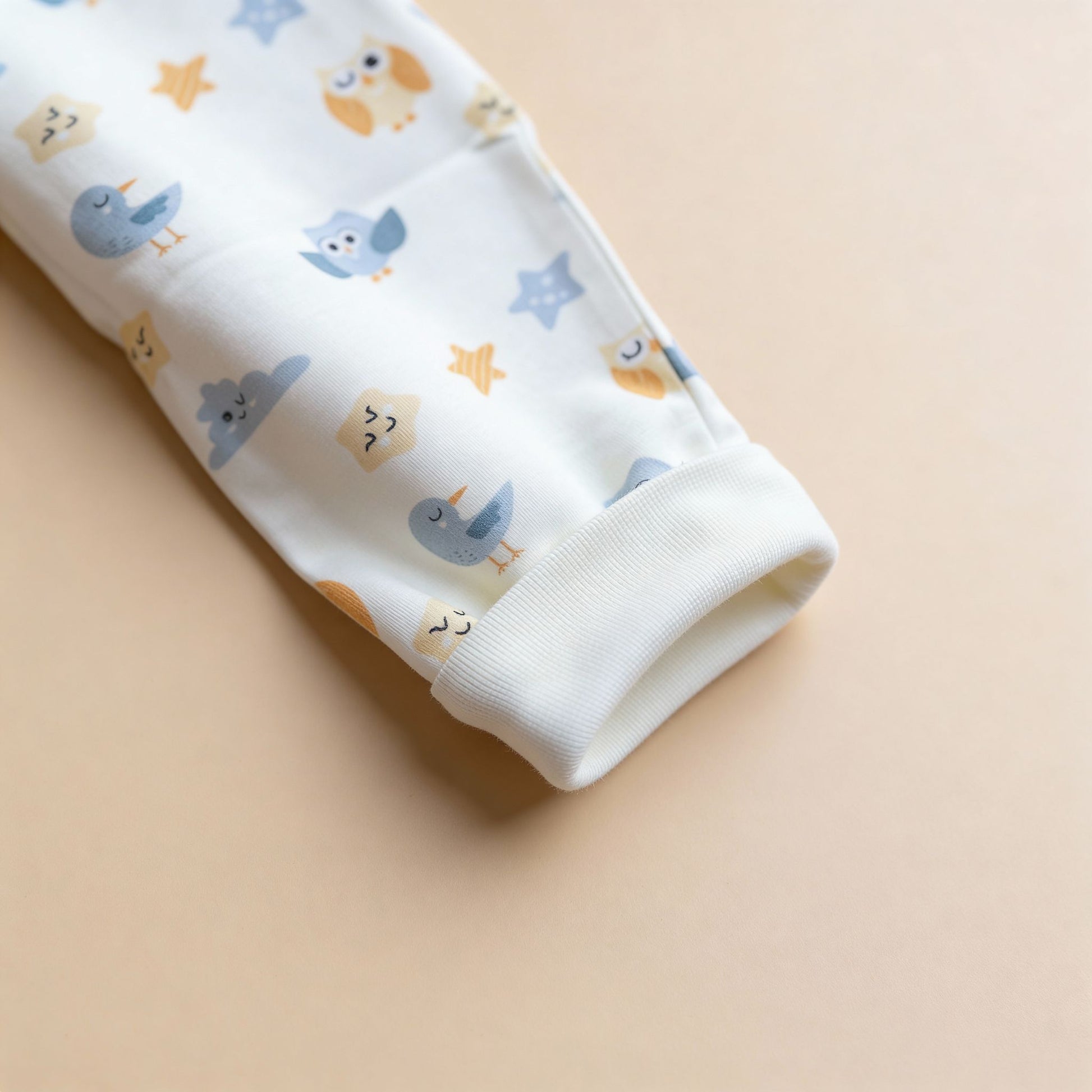 Detaljbild av ekologiska babybyxor från kollektionen Himlens Vänner med fågel- och stjärnmönster