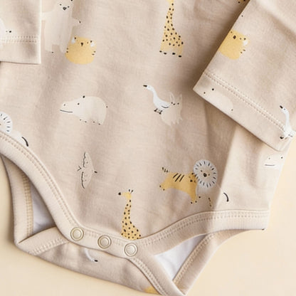 Detaljbild av ekologisk babybody från kollektionen Safari Vänner med knappar i grenen och djurmönster i beige toner
