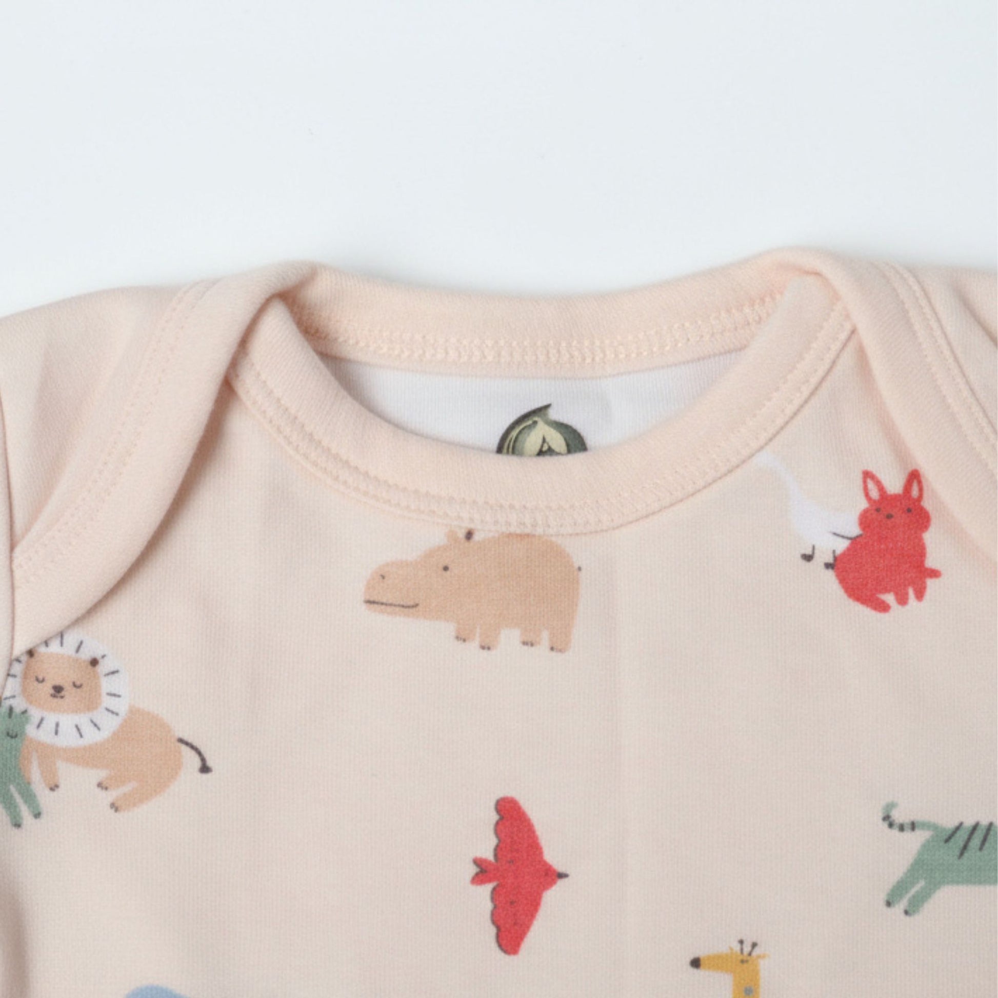 Detaljbild av ekologisk babybody från kollektionen Safari Vänner med halsringning och djurmönster på rosa botten