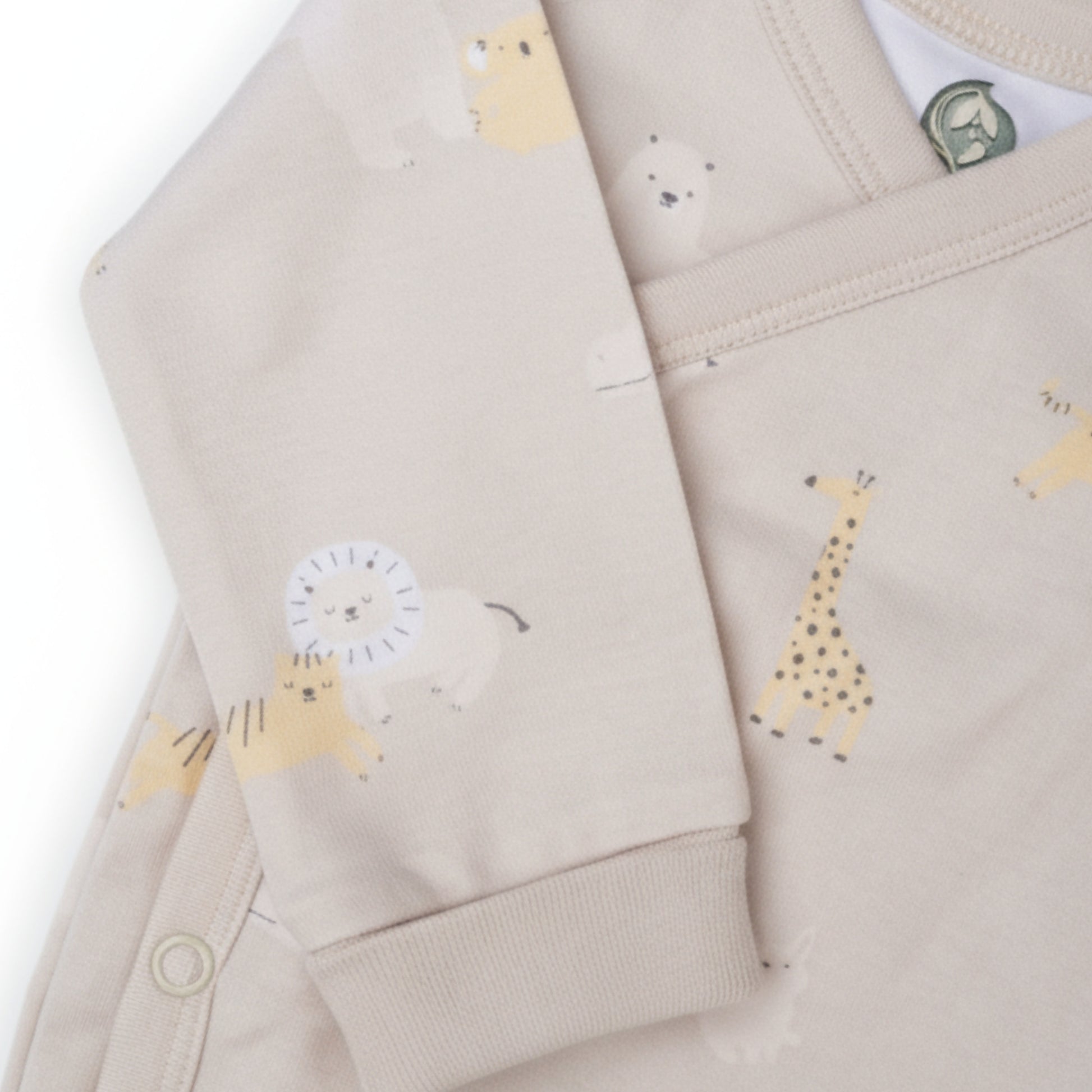 Detaljbild av ekologisk omlottbody från kollektionen Safari Vänner med beige ärmmudd och djurmönster