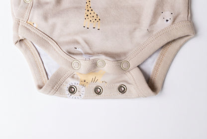 Detaljbild av ekologisk omlottbody från kollektionen Safari Vänner med knappar i grenen och djurmönster i beige toner