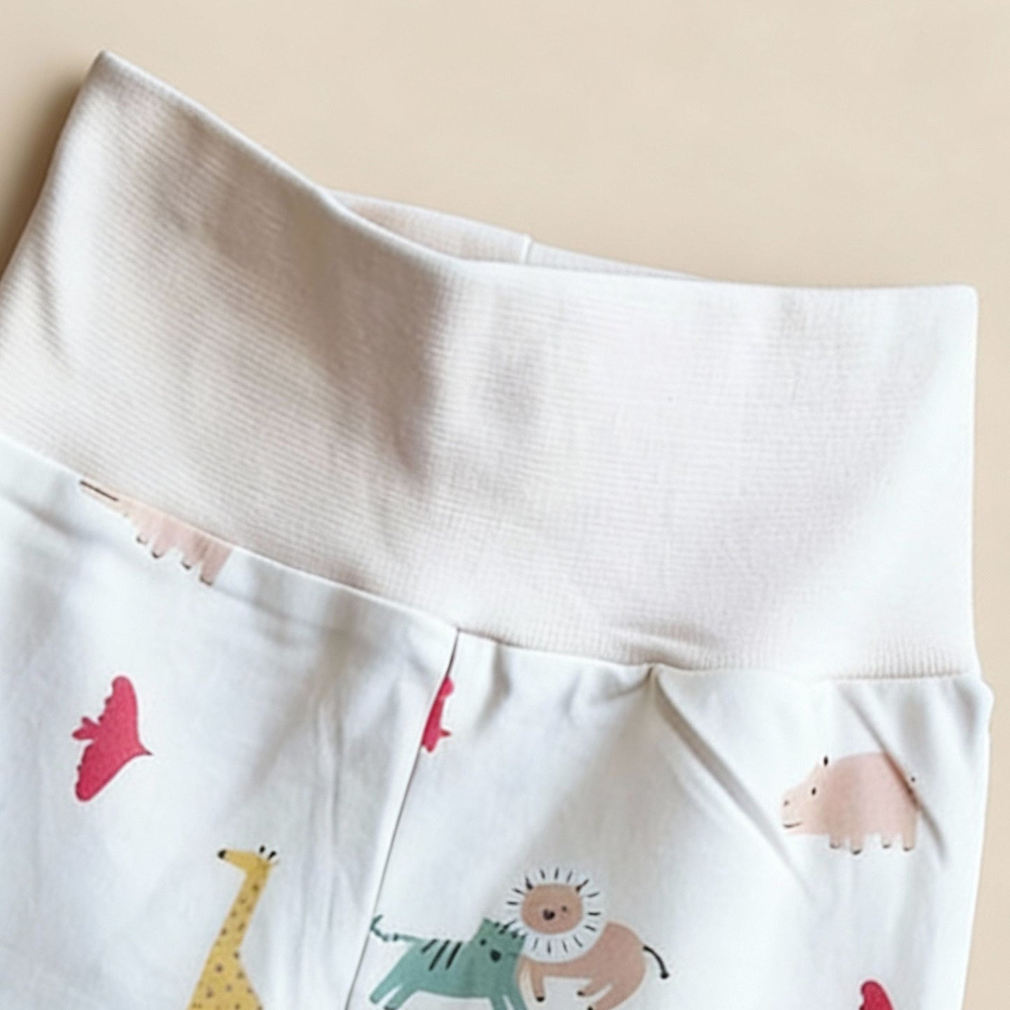 Detaljbild av ekologiska babybyxor från kollektionen Safari Vänner med mjuk vit midja och färgglatt djurmönster