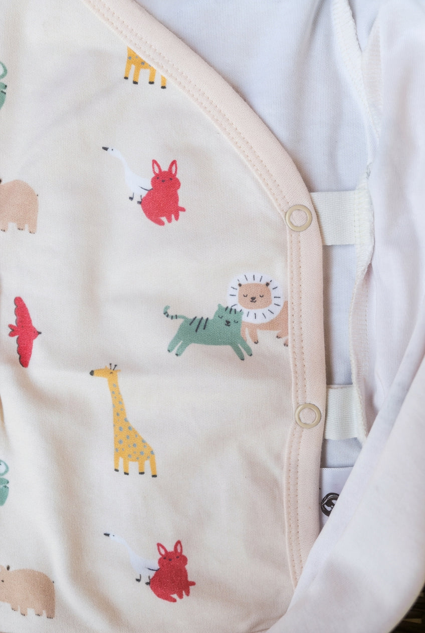 Detaljbild av Snödroppen omlottbody med Safari Vänner-djurmönster och sidoknappar för enkel påklädning